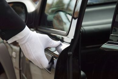 Hand with white glove opening car door.