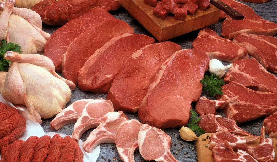 Assorted raw meats including beef, chicken, and pork arranged with herbs and garlic.