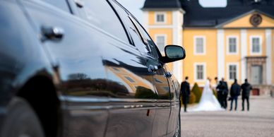 Black 10 passenger limousine picking up couple from wedding ceremony