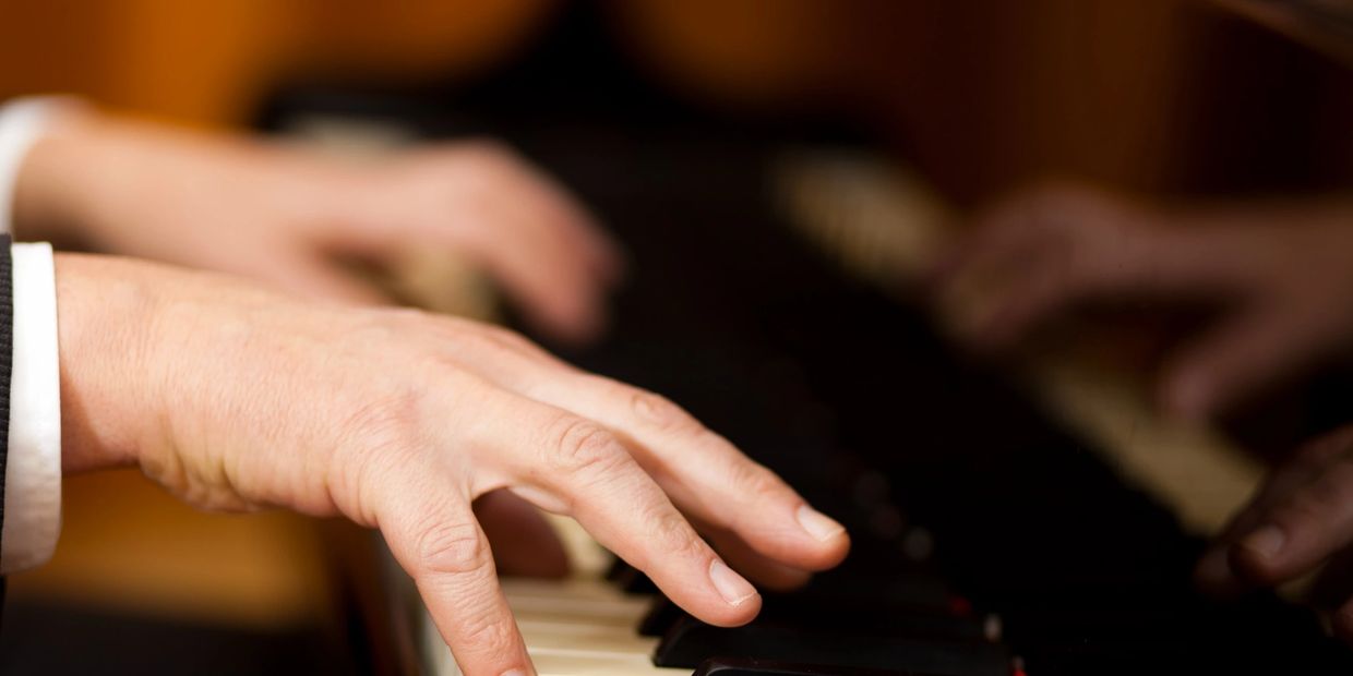 Close-up of hands playing piano keys.