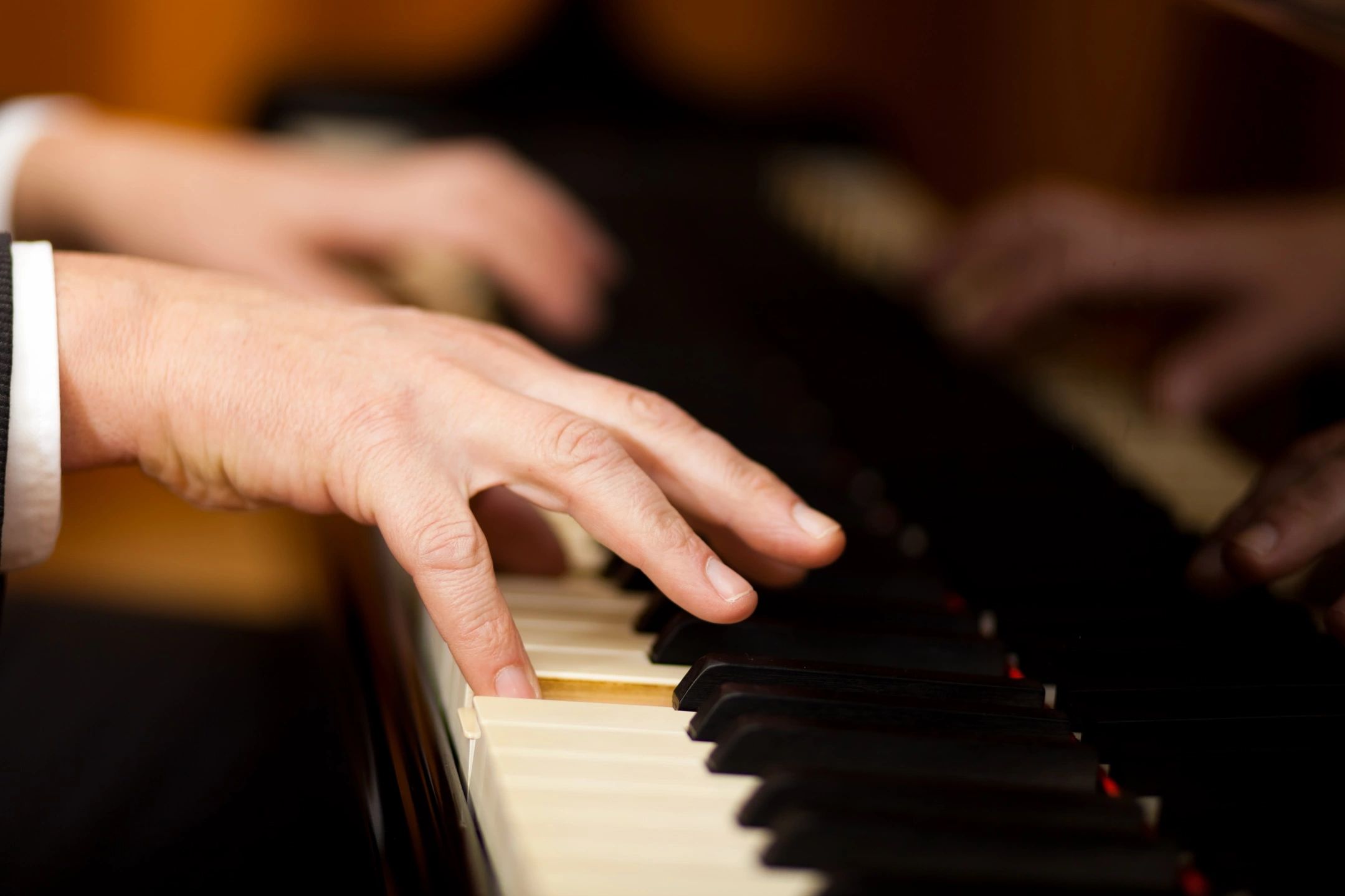 Close-up of hands playing piano keys with focus on precise finger placement.