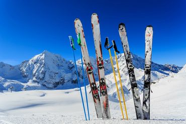 2 pair of skis sticking vertically out of the snow, with epic view.  Made possible by racks.