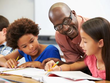 Teacher helping students with their studies in a classroom.