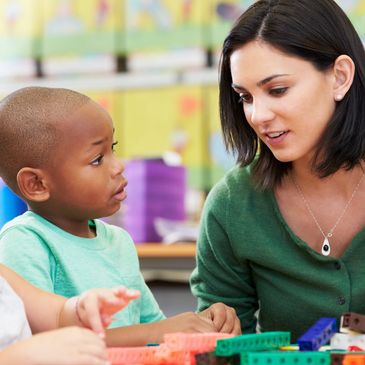 Teacher talking to a young student in class.