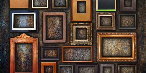 An eclectic display of different shapes and sizes of frames all arranged closely on a wall.