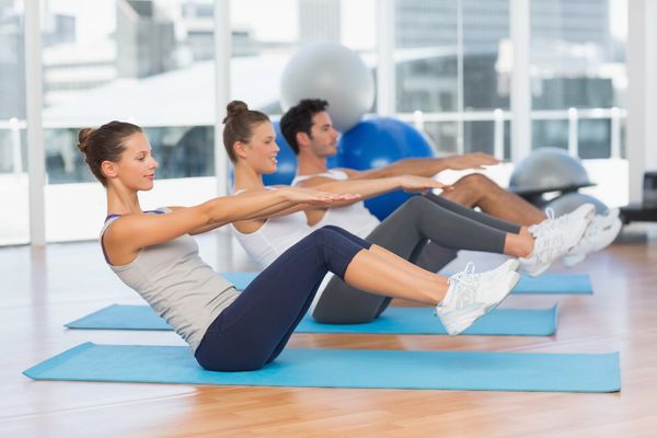 clients in pilates mat class, holding the teaser position.