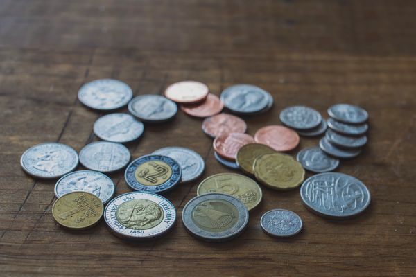 A collection of various coins spread on a wooden surface.