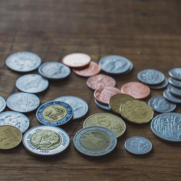 Assorted coins from various currencies laid out on a wooden surface.