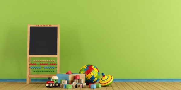 Children's toys and a chalkboard against a green wall.