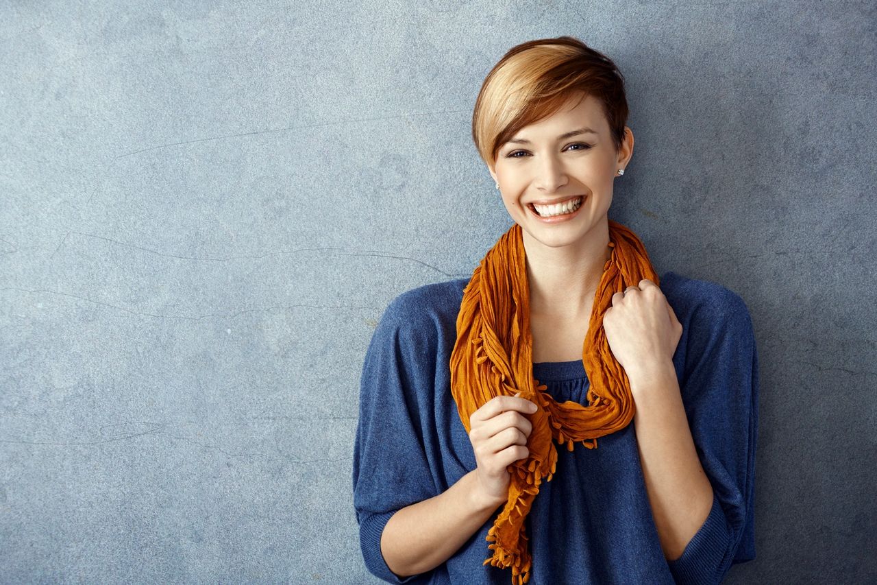 A happy person stands on the wall with a beautiful smile displaying her positivity.