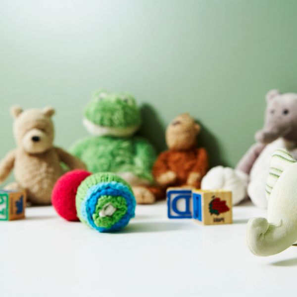 Soft toys and colorful blocks arranged on a white surface with a green background.