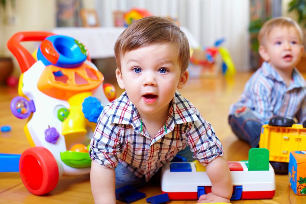 Two toddlers playing with toys indoors.