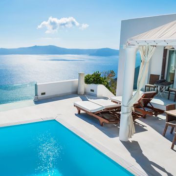 Luxury poolside lounge with ocean view and sunbeds under a canopy.