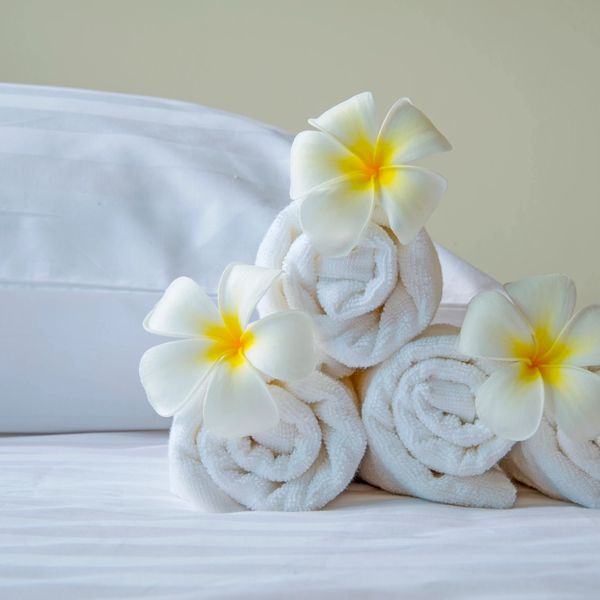 treatment bed display with pillow, rolled towels & hibiscus flowers