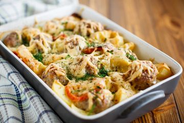 Baked pasta with meatballs and melted cheese in a white casserole dish.