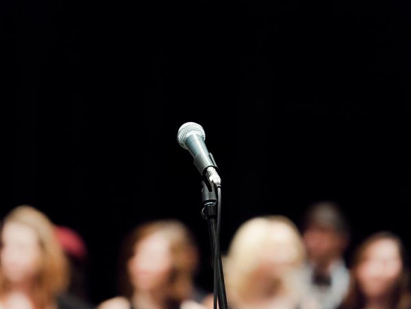 Microphone on stand with blurred audience in background.