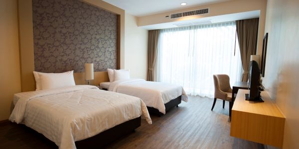 Modern hotel room with two single beds and a large window.
