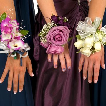Three hands wearing elegant floral corsages for a formal event.