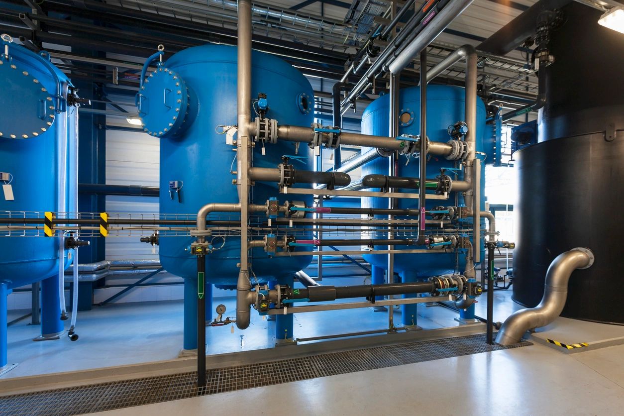 Industrial water treatment tanks with interconnected pipes inside a facility.
