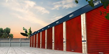 A row of red storage unit doors at sunset with surrounding greenery.