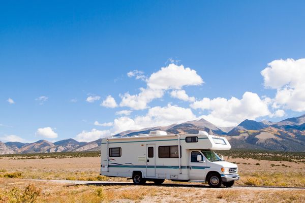 RV parked in a desert landscape with mountains in the background.