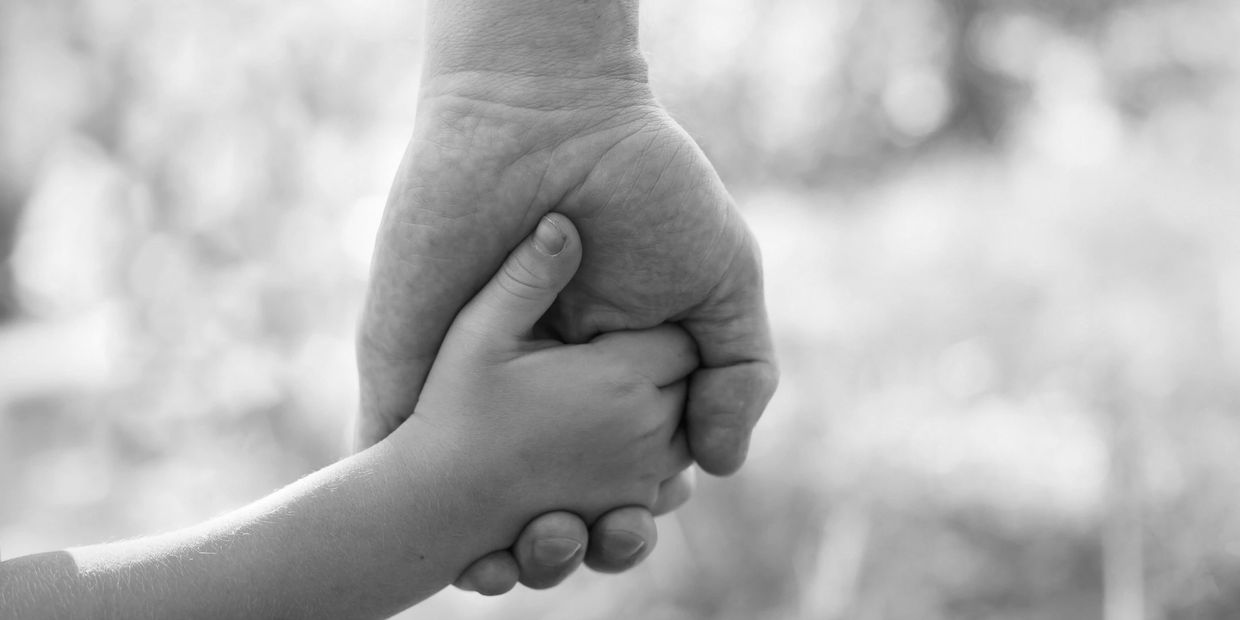 An adult and child holding hands