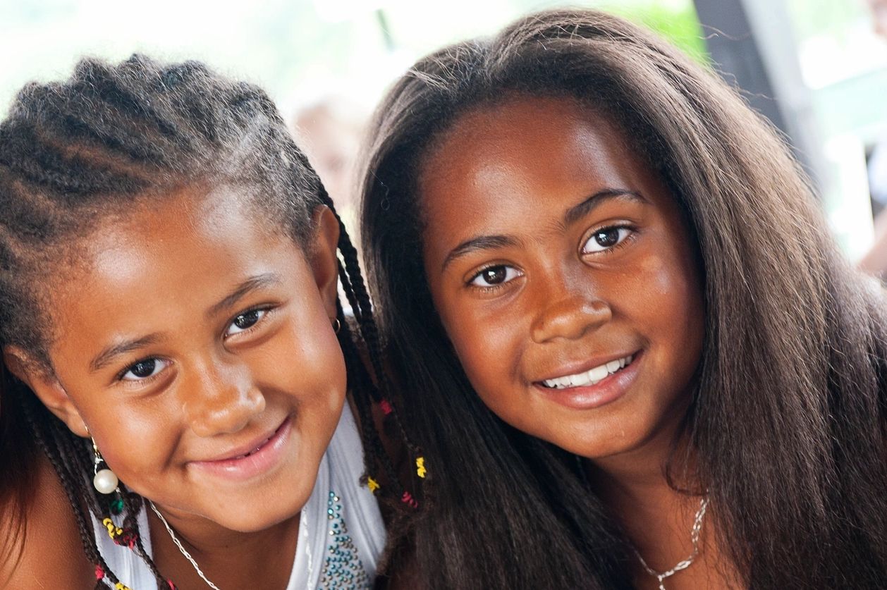 Two smiling girls with braided and loose hair close together.
