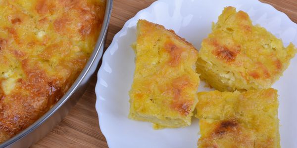 Golden baked cornbread squares on a white plate beside a baking dish.