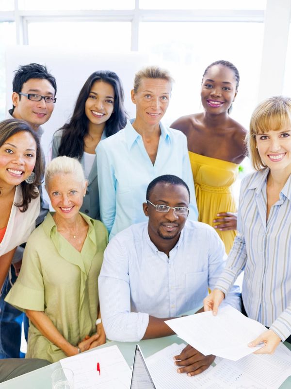 Group of people smiling at camera while consulting documents on a table