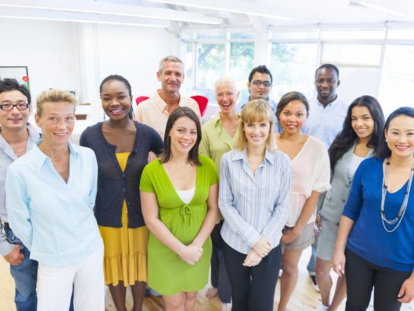 A diverse group of professionals smiling in a bright office space.