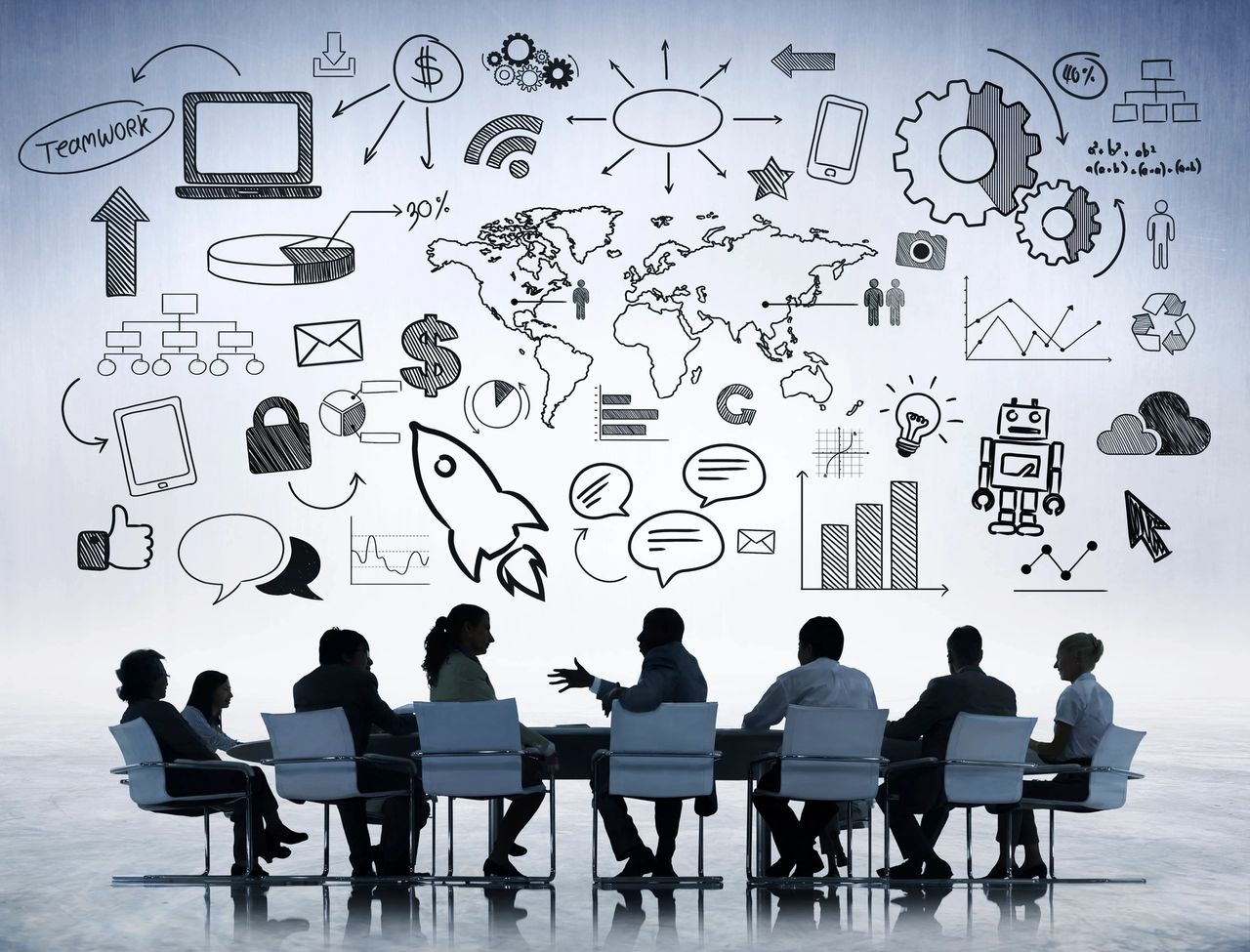 A team of people sit at a round table meeting with all of their ideas on the wall behind them.