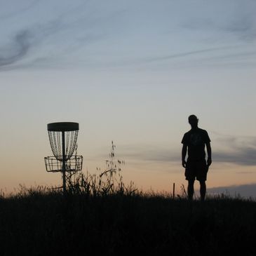 A silhouette of a man standing next to a basket at dusk.