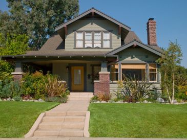 A charming Craftsman-style house with a green lawn.