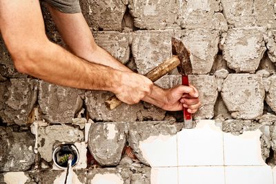 Man Chiseling Tiles off of stone with a Hammer