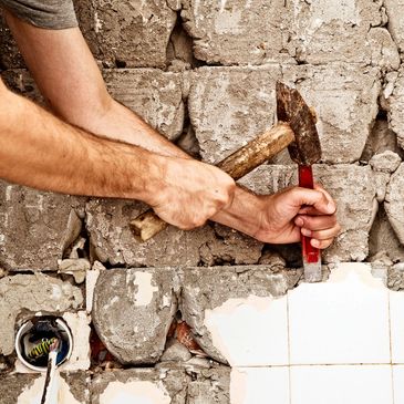 Worker removing tile from wall.