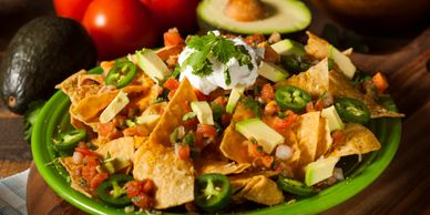 Plate of loaded nachos with jalapeños, sour cream, and avocado.