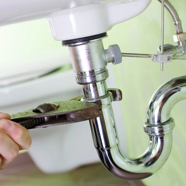 Plumber working on a bathroom basin waste pipe. 