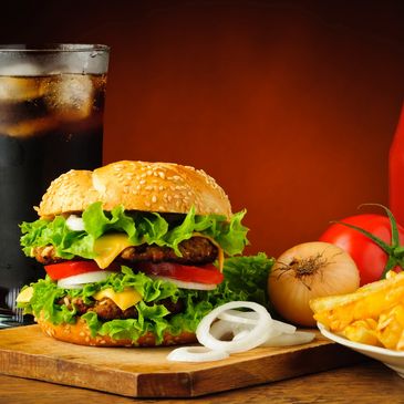 Delicious double cheeseburger with fresh lettuce, tomato, and onions, served with fries and a soda.