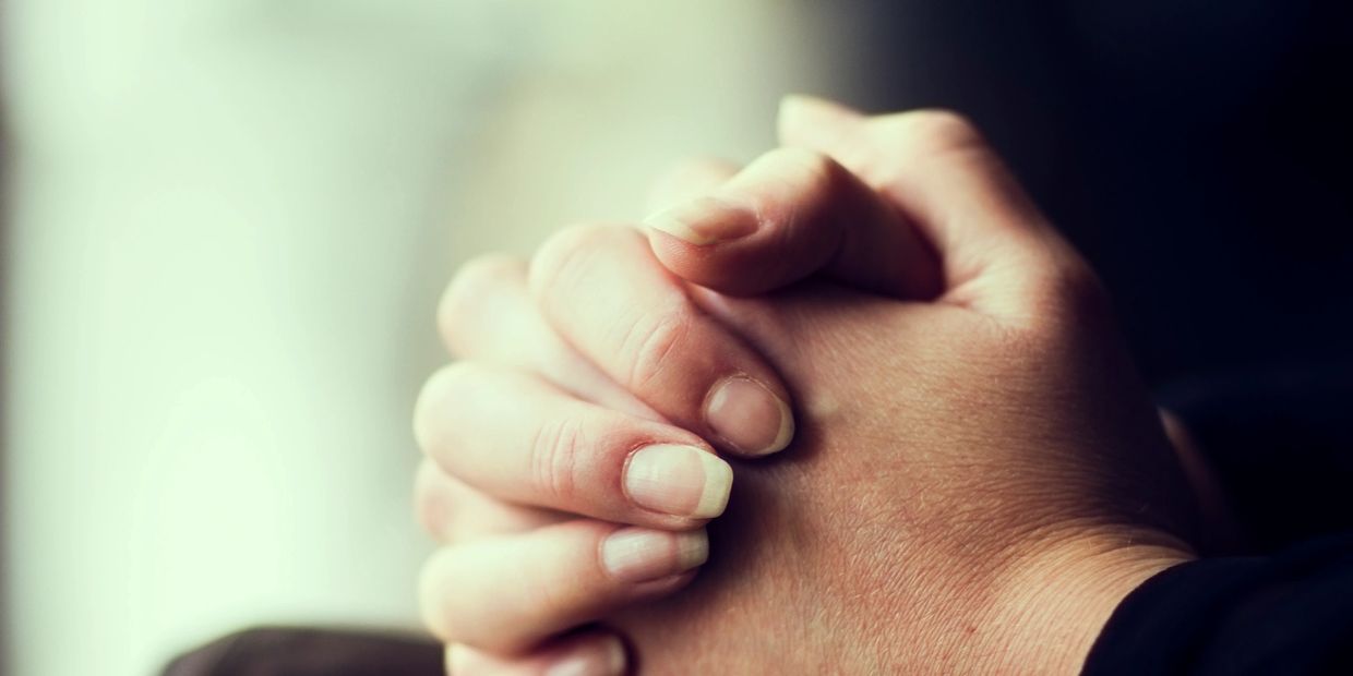Close-up of hands clasped together in a gesture of prayer or contemplation.