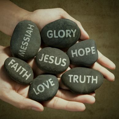 Black stones with inspirational words held in hands.