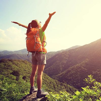 Woman hiking on a peak, arms out to the sunlight