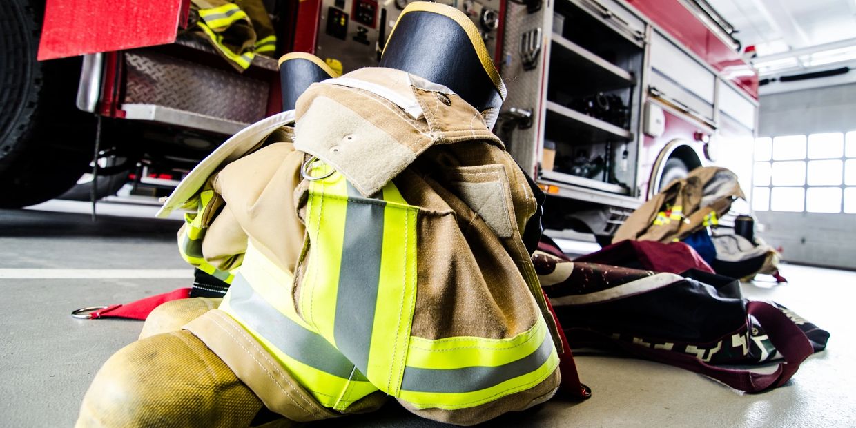 Firefighter gear neatly placed near a fire truck inside a station.