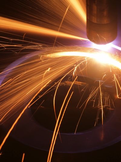 Bright sparks flying from metal cutting or welding work in a dark setting.