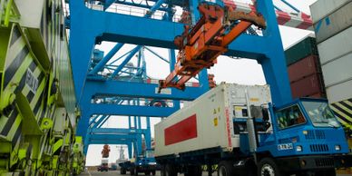 Cranes at a port unloading cargo containers onto a truck