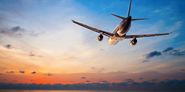 Airplane flying over ocean into the sunset on vacation