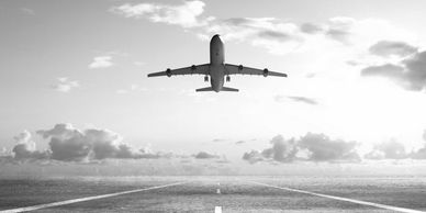 Airplane taking off from runway into a bright sky.