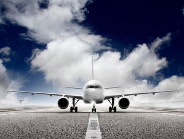 A commercial airplane on a runway under a cloudy sky.