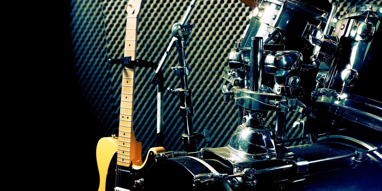 Electric guitar and drum kit in a music studio with soundproofing.