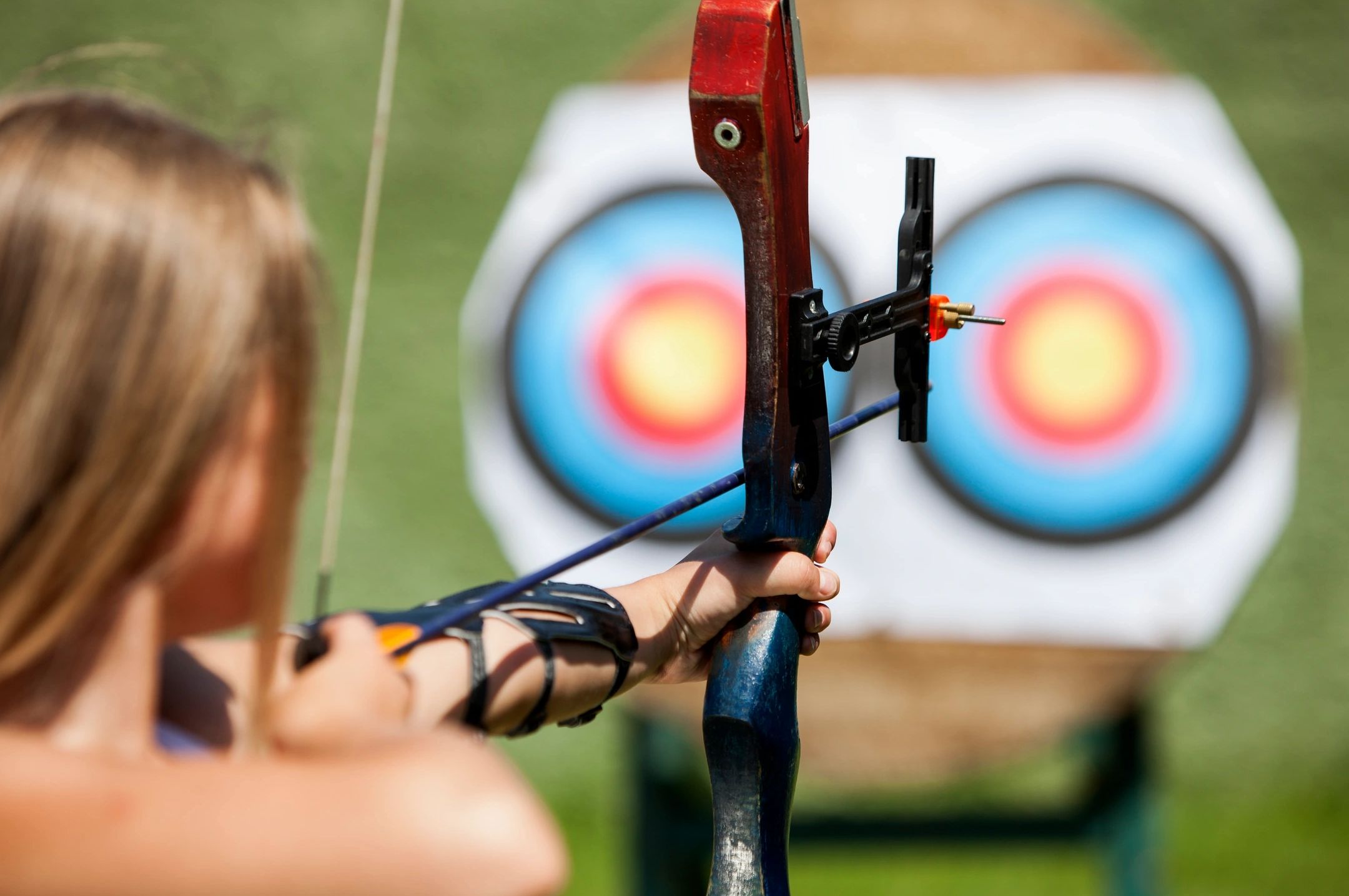 Person aiming a bow and arrow at an archery target.