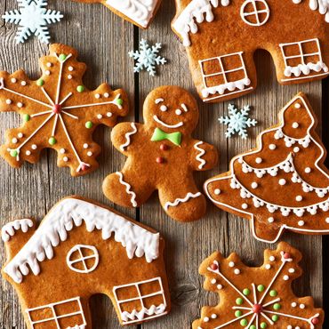 Festive gingerbread cookies decorated with icing and candy on wooden surface.